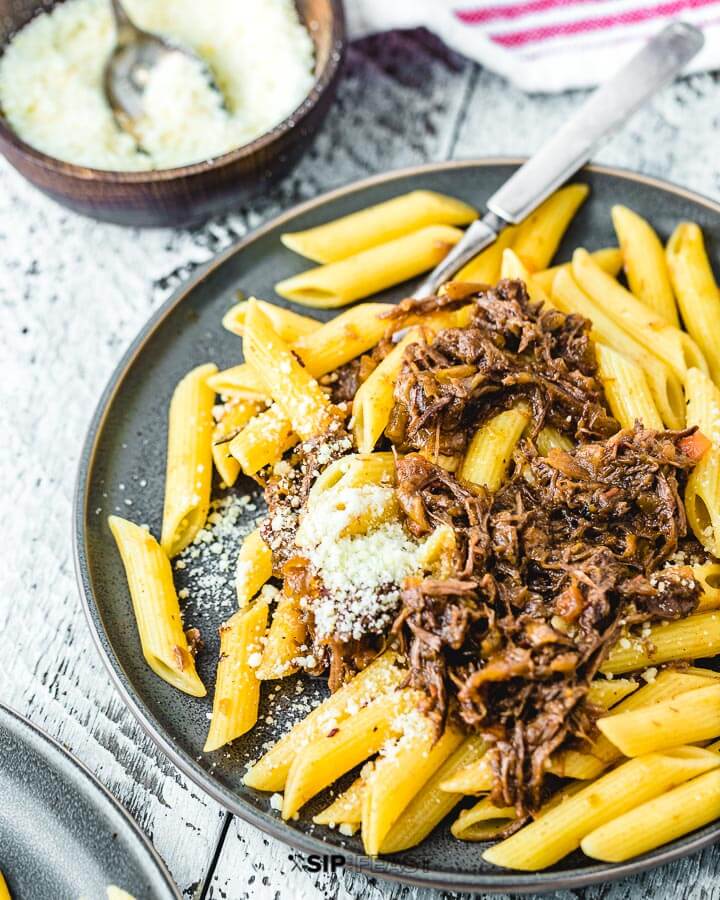 Plate of Pasta alla Genovese with grated parmesan cheese on the side.