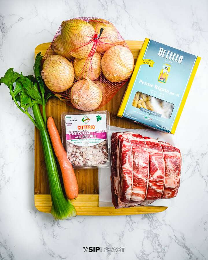 Ingredients shown: onions, penne pasta, celery, carrots, pancetta, and a chuck roast.