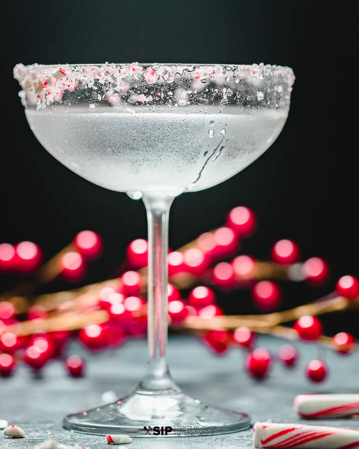 Candy Cane cocktail with berries and candy canes in background.