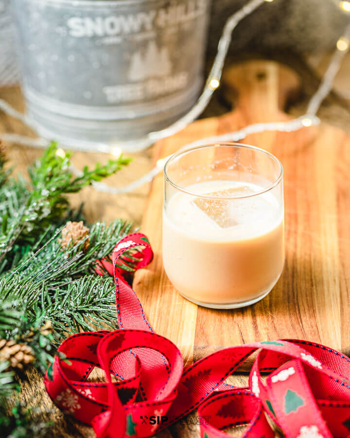 A glass with the eggnog white Russian,with ribbon and pine leaves in the background.