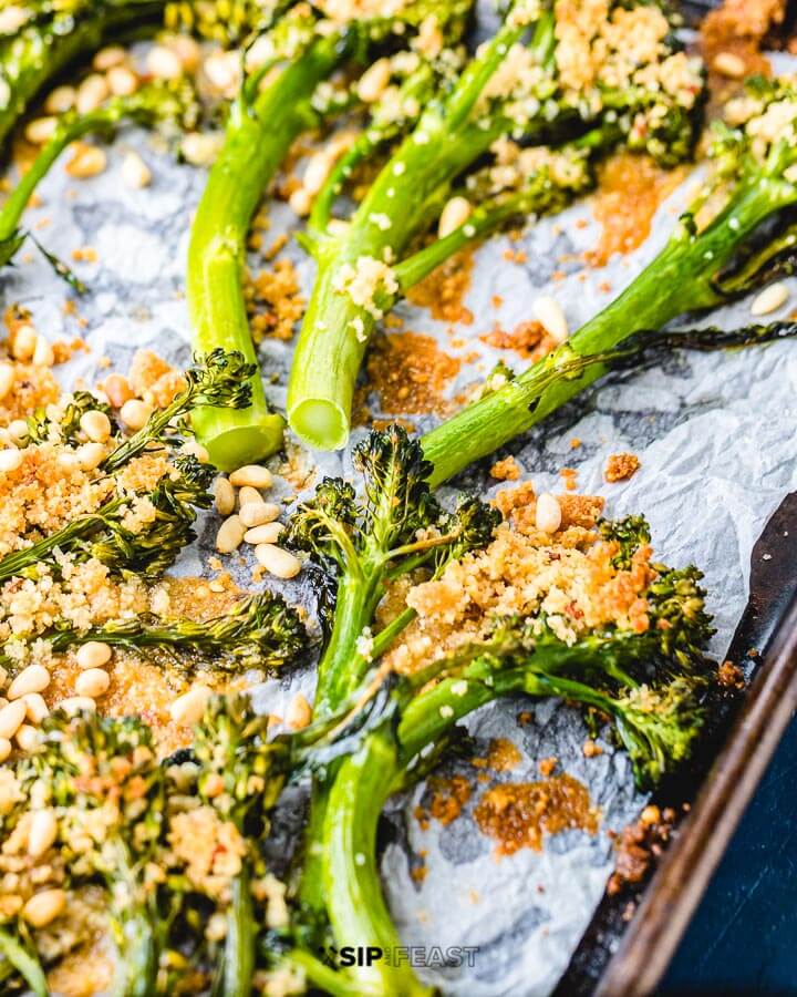 Parchment paper lined sheet pan with roasted baby broccoli.