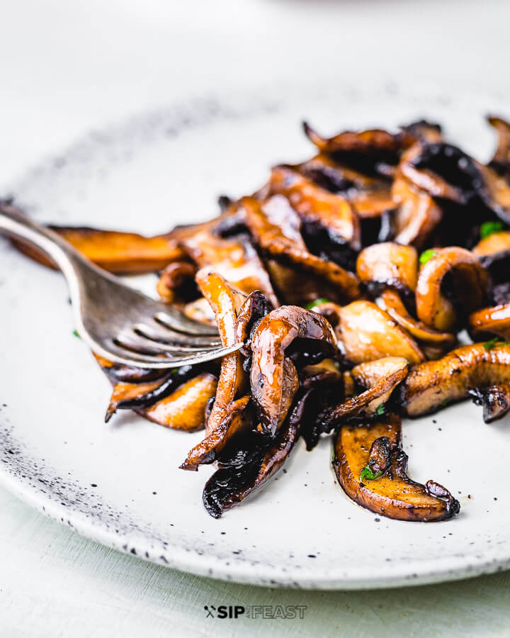 White plate and fork with balsamic sauteed portobello mushrooms.