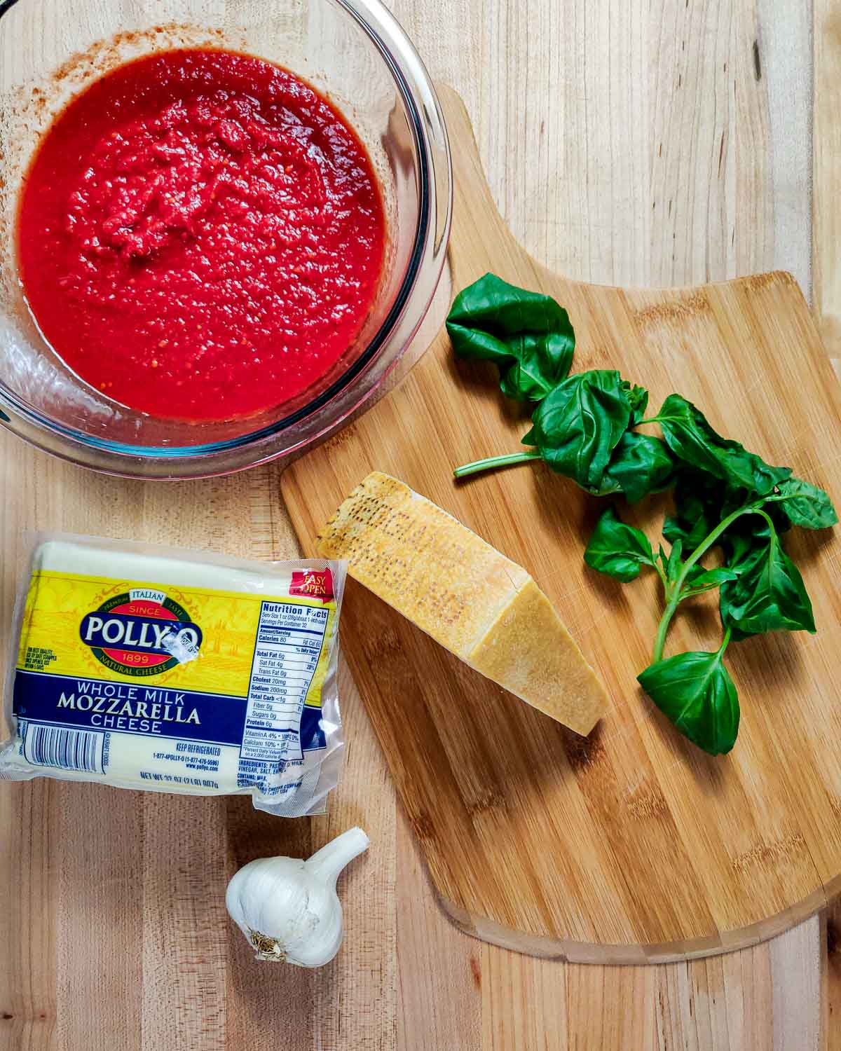 Ingredients shown: marinara sauce, basil, Parmigiano Reggiano, mozzarella, and garlic.