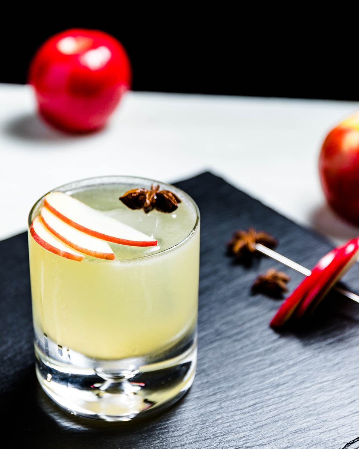 Apple margarita on black slate tile with apple in background.