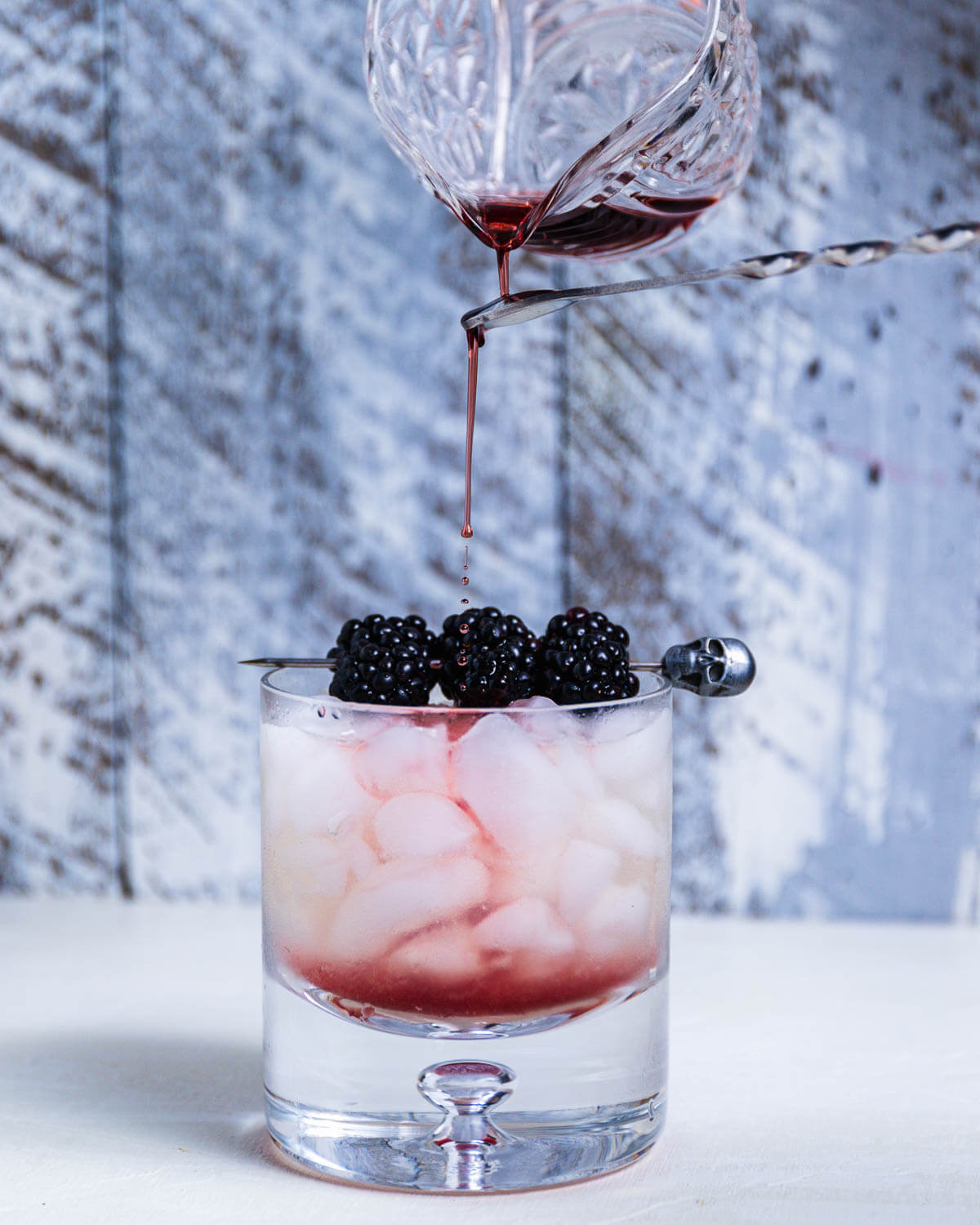 Pouring Creme de Mure in rocks glass with ice.