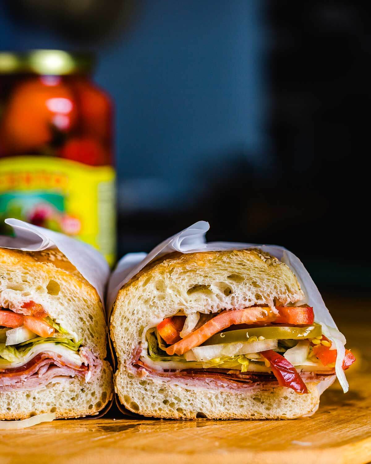 Italian Hero wrapped in deli paper on cutting board.