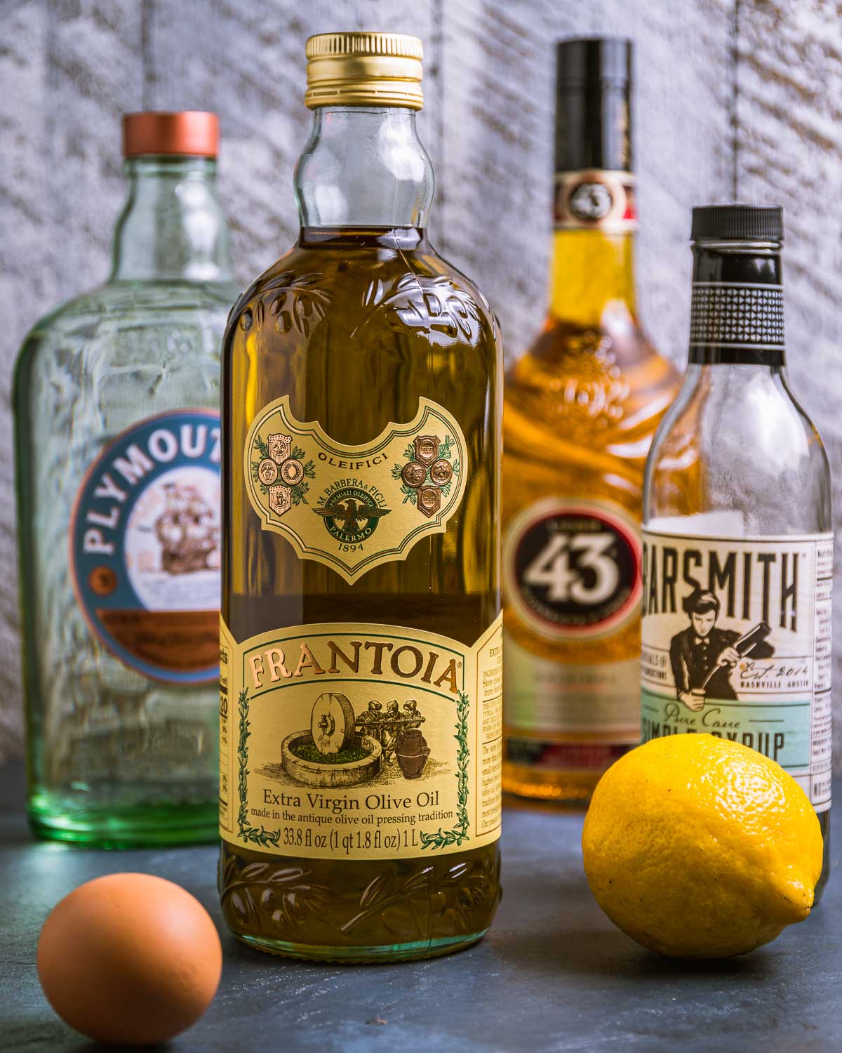 Ingredients shown: gin, olive oil, 43 liqueur, simple syrup, lemon, and egg.