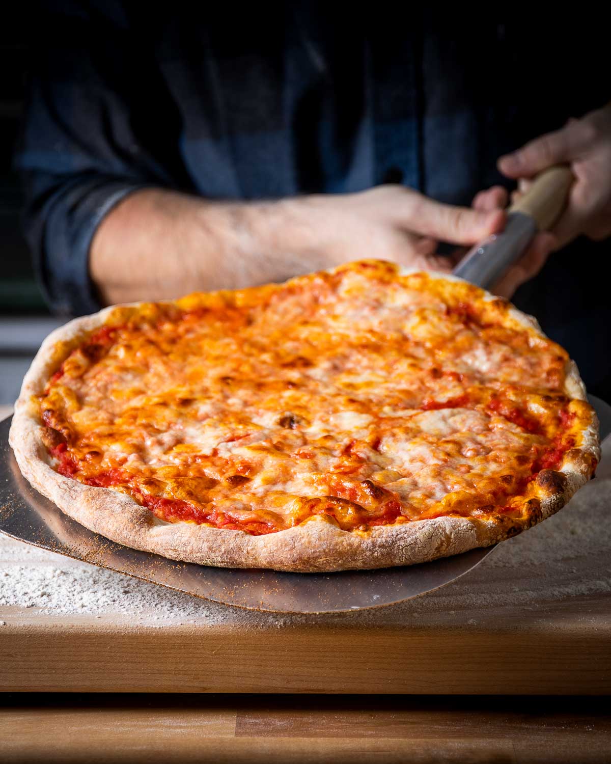 New York pizza held with metal pizza peel.