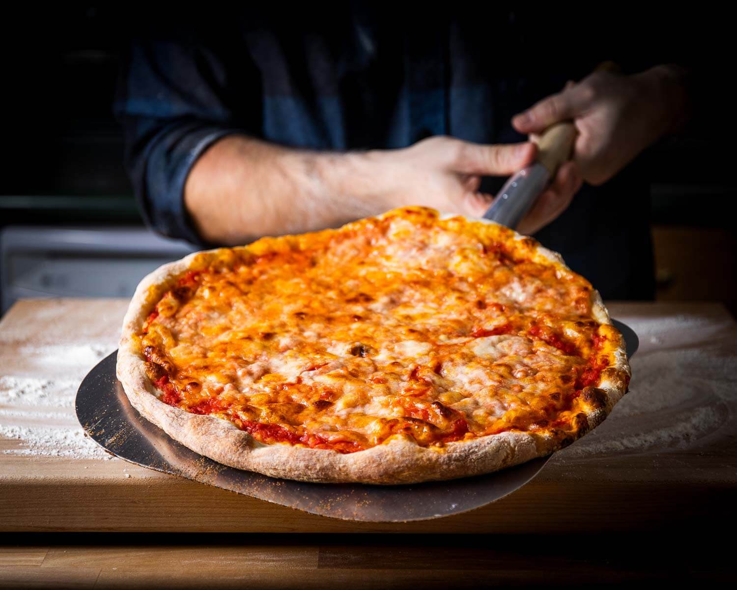 New York pizza held with metal peel.