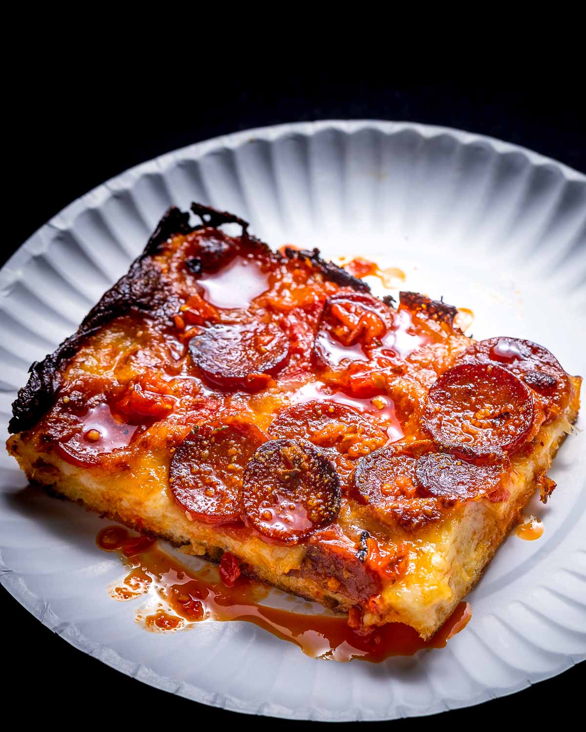 Square pepperoni pizza slice in white plate.