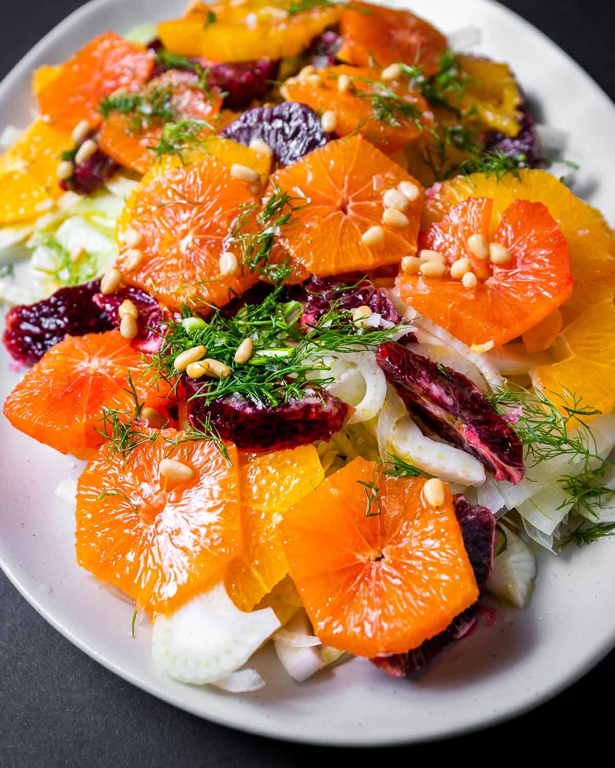 White platter with oranges, fennel, pine nuts, and fennel fronds.