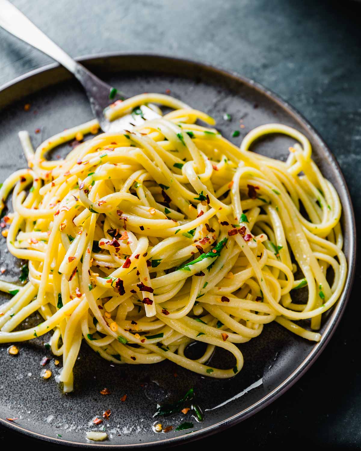 Linguine aglio e olio in grey plate with fork.