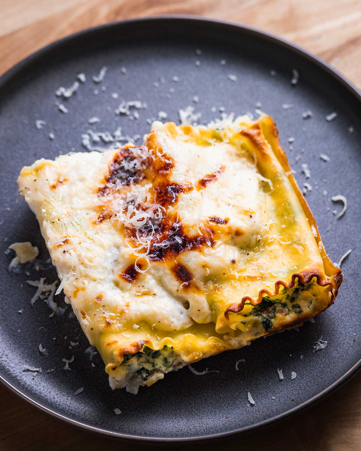 Grey plate with two pieces of lasagna rolls with white sauce.