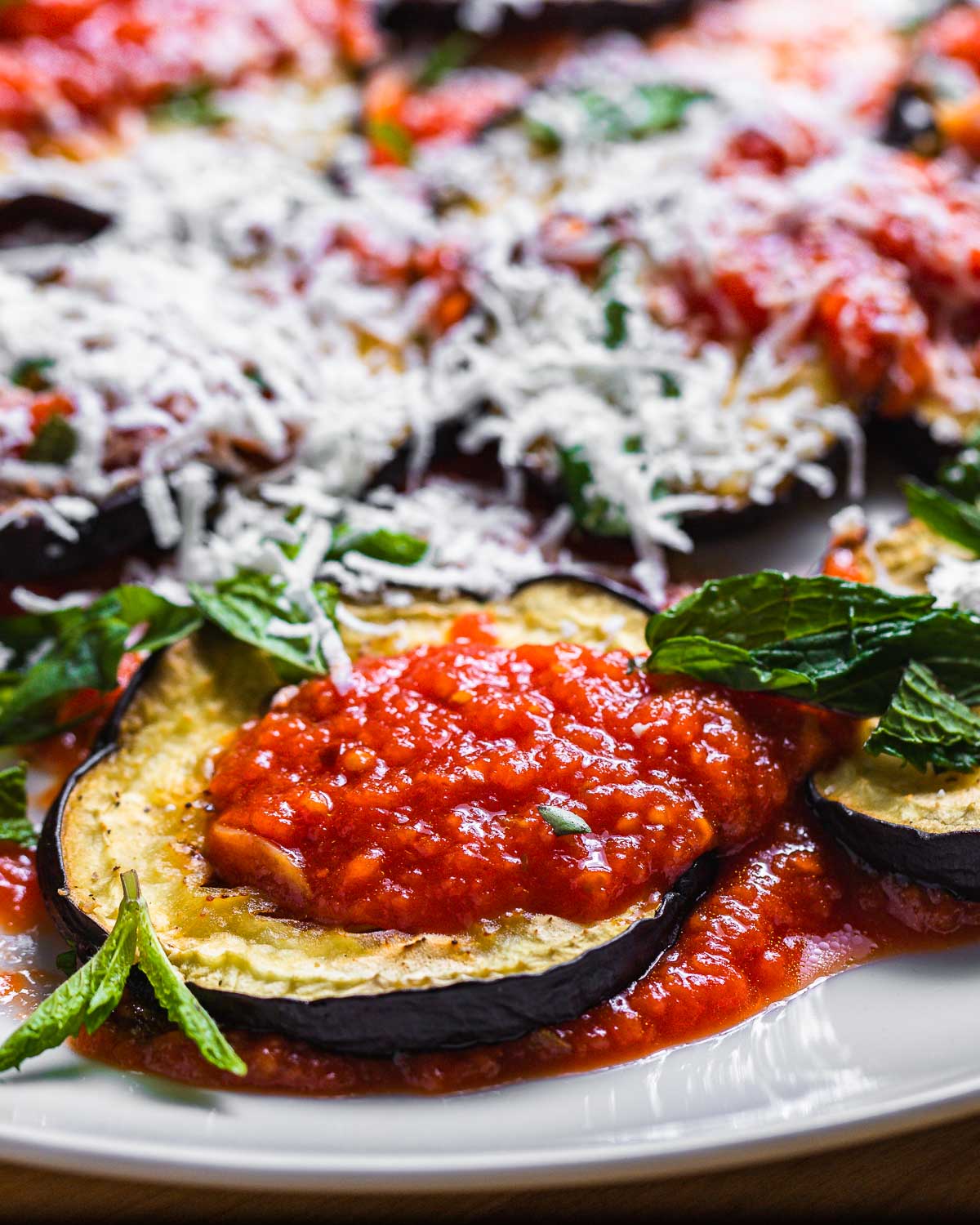 Close up shot of one roasted eggplant disc with sauce.