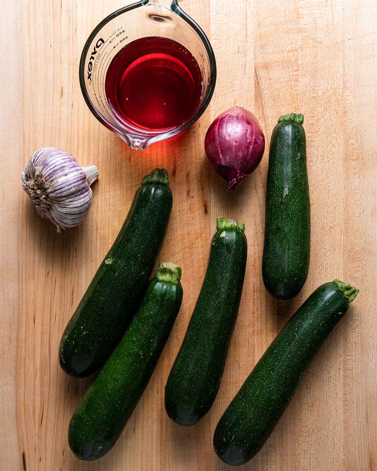 Ingredients shown: red wine vinegar, garlic, red onion, and 5 zucchini on cutting board.