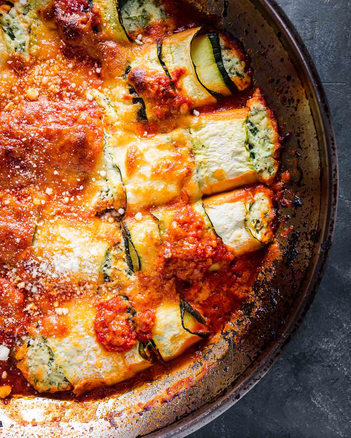 Zucchini rollatini in metal pan on blue background.