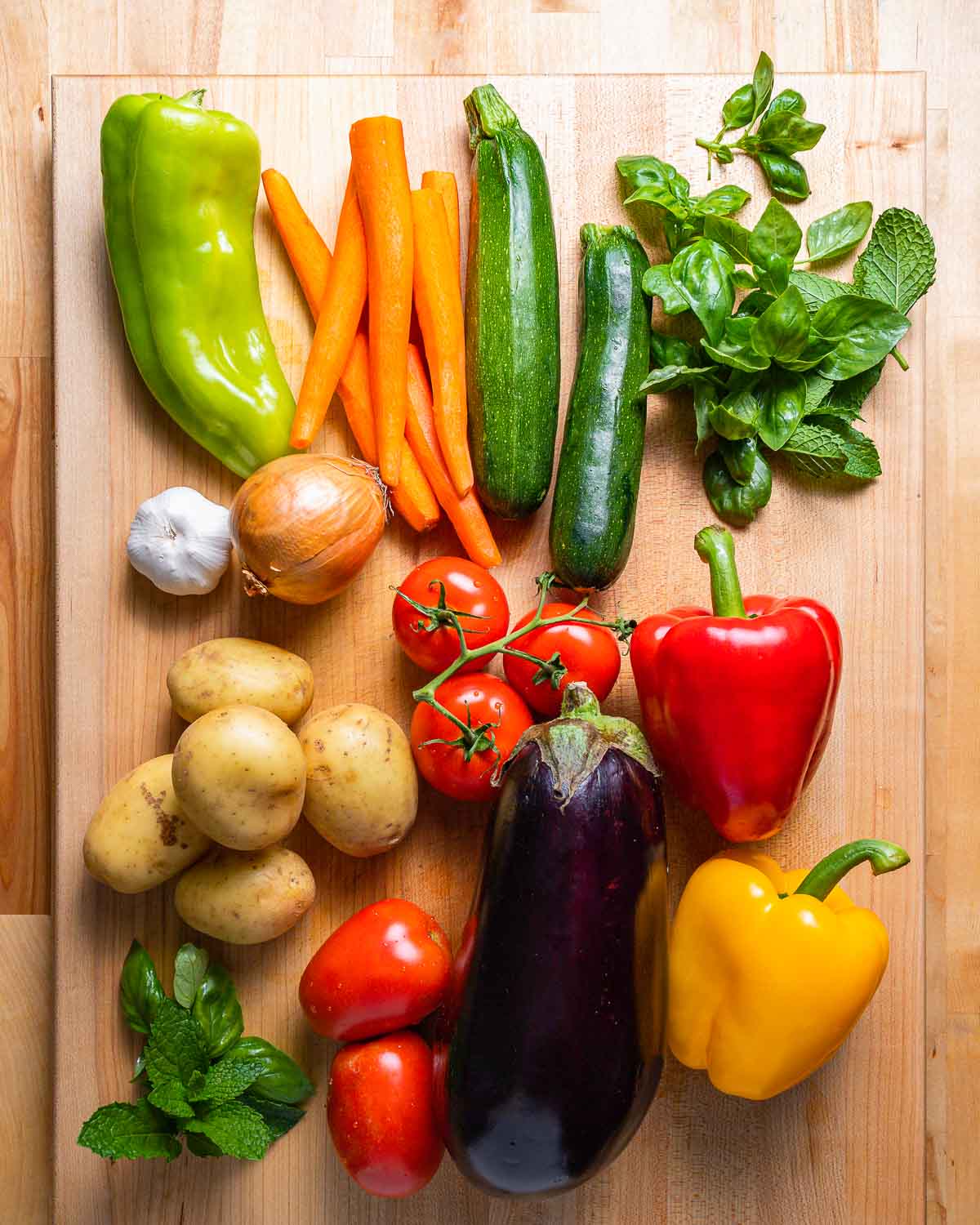 Vegetables shown: Peppers, carrots, zucchini, herbs, potatoes, tomatoes, eggplant, garlic, and onion.