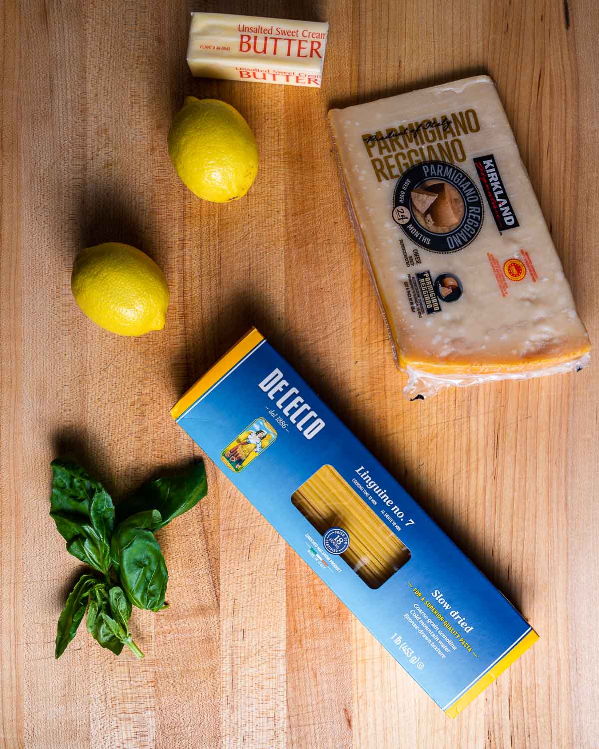 Ingredients shown: butter, lemons, parmesan cheese, basil, and box of linguine.