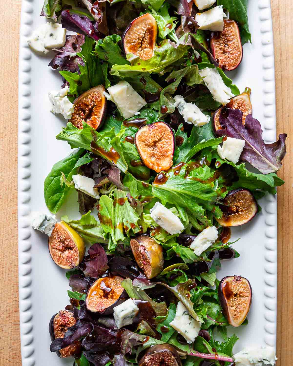 Overhead shot of large white platter with roasted fig salad.