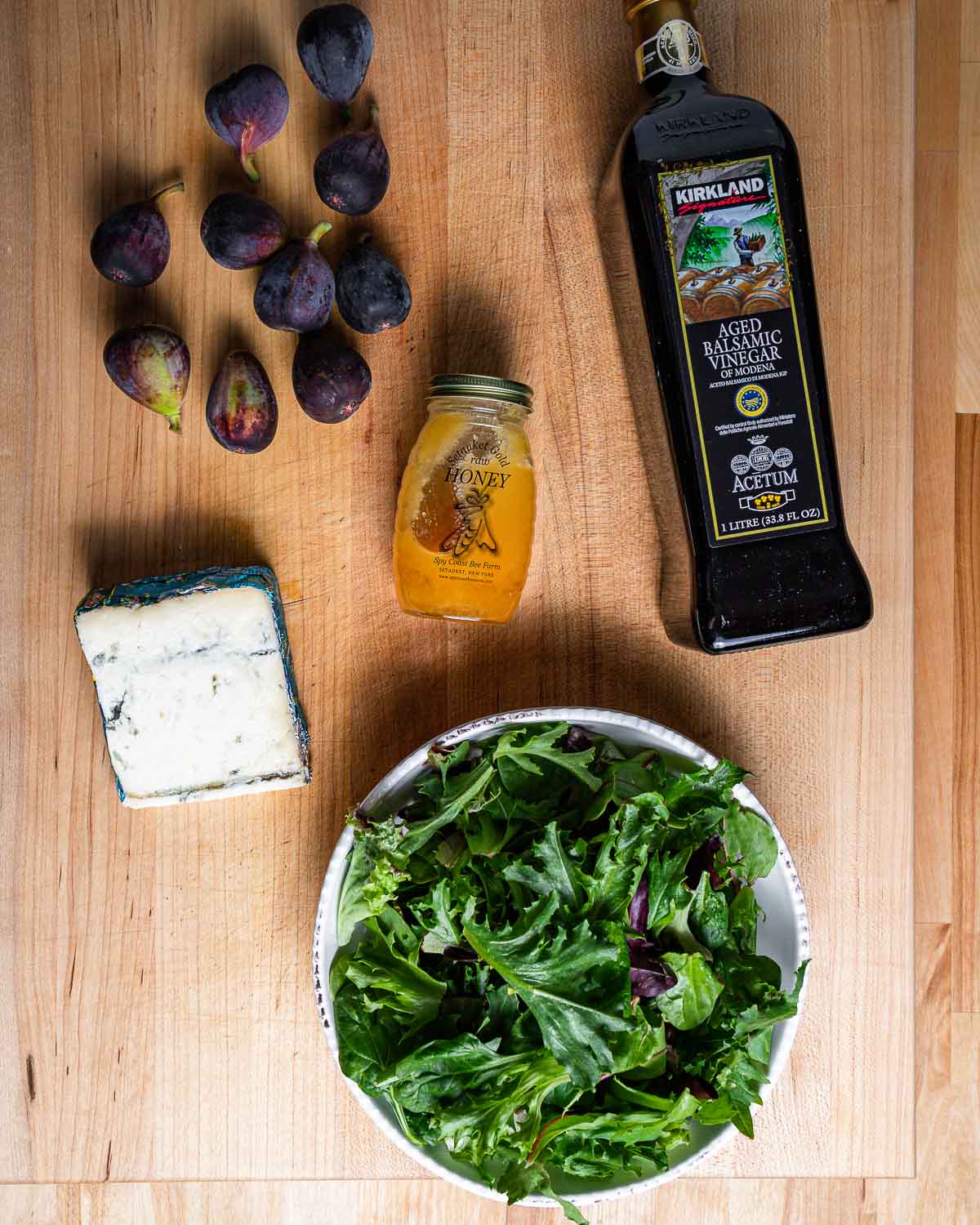 Ingredients shown: figs, honey, balsamic vinegar, gorgonzola cheese, and mixed greens in bowl.