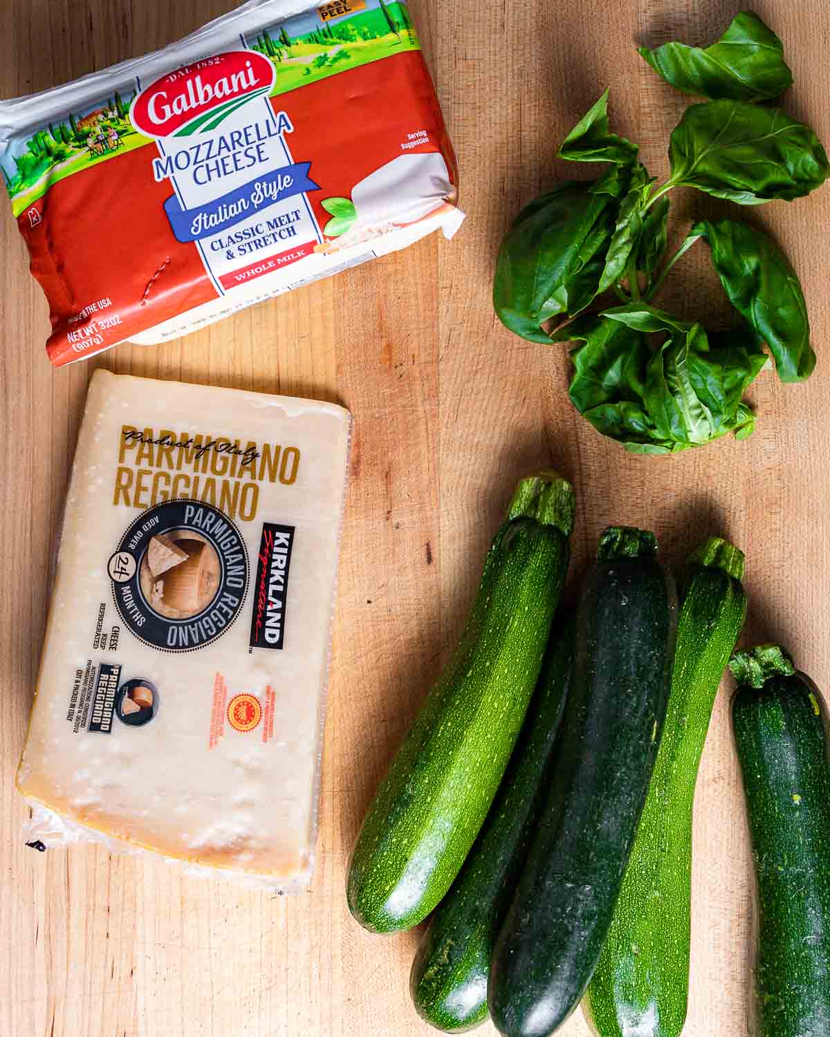 Ingredients shown: mozzarella, basil, parmesan block, and 4 zucchini.