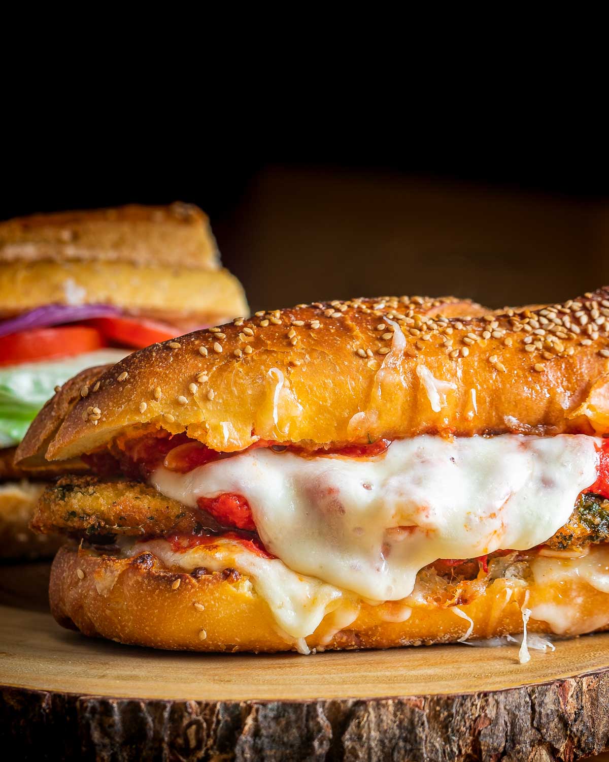 Chicken parm hero sandwich on wood board.