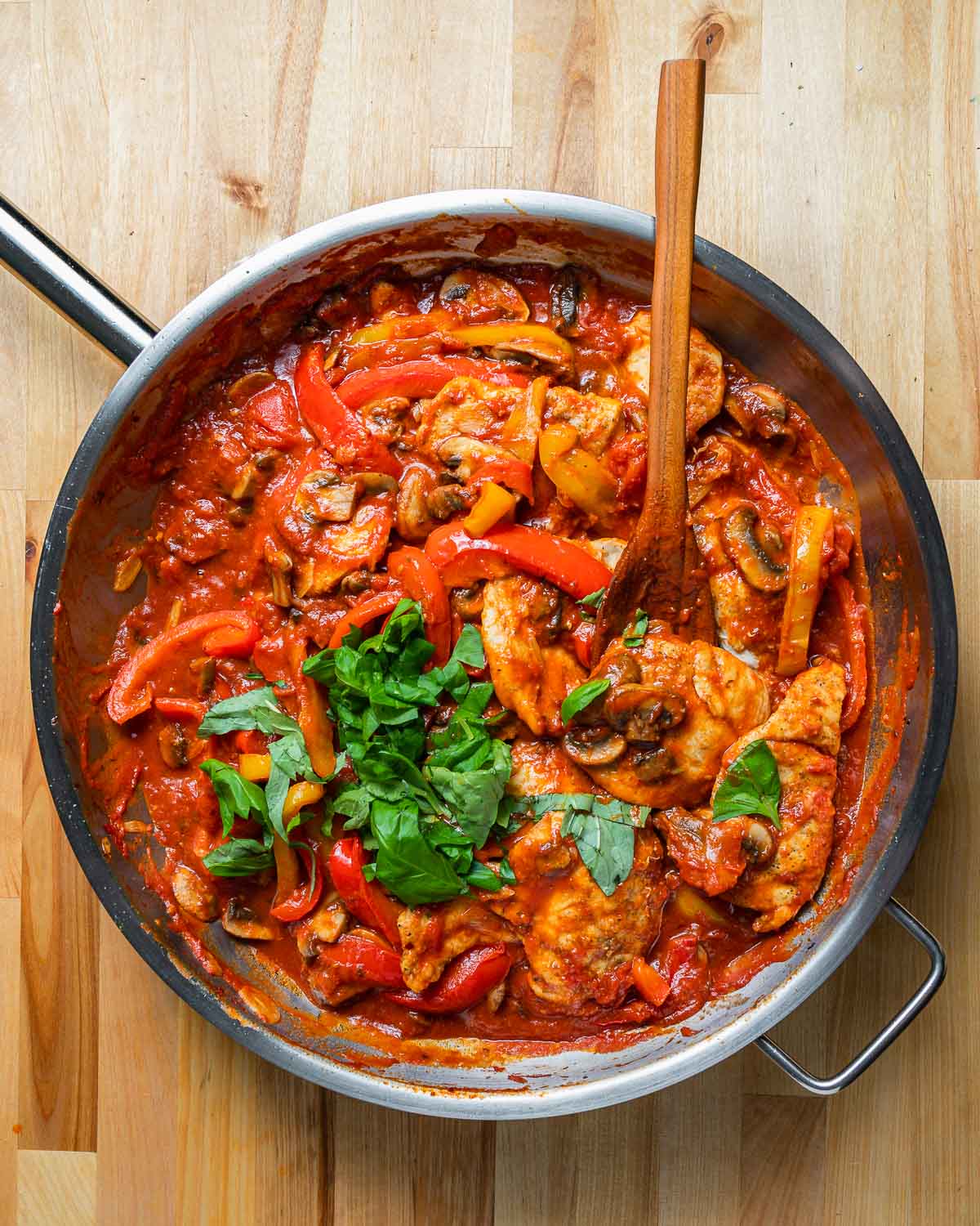 Overheat shot of large pan with chicken and peppers in tomato sauce.