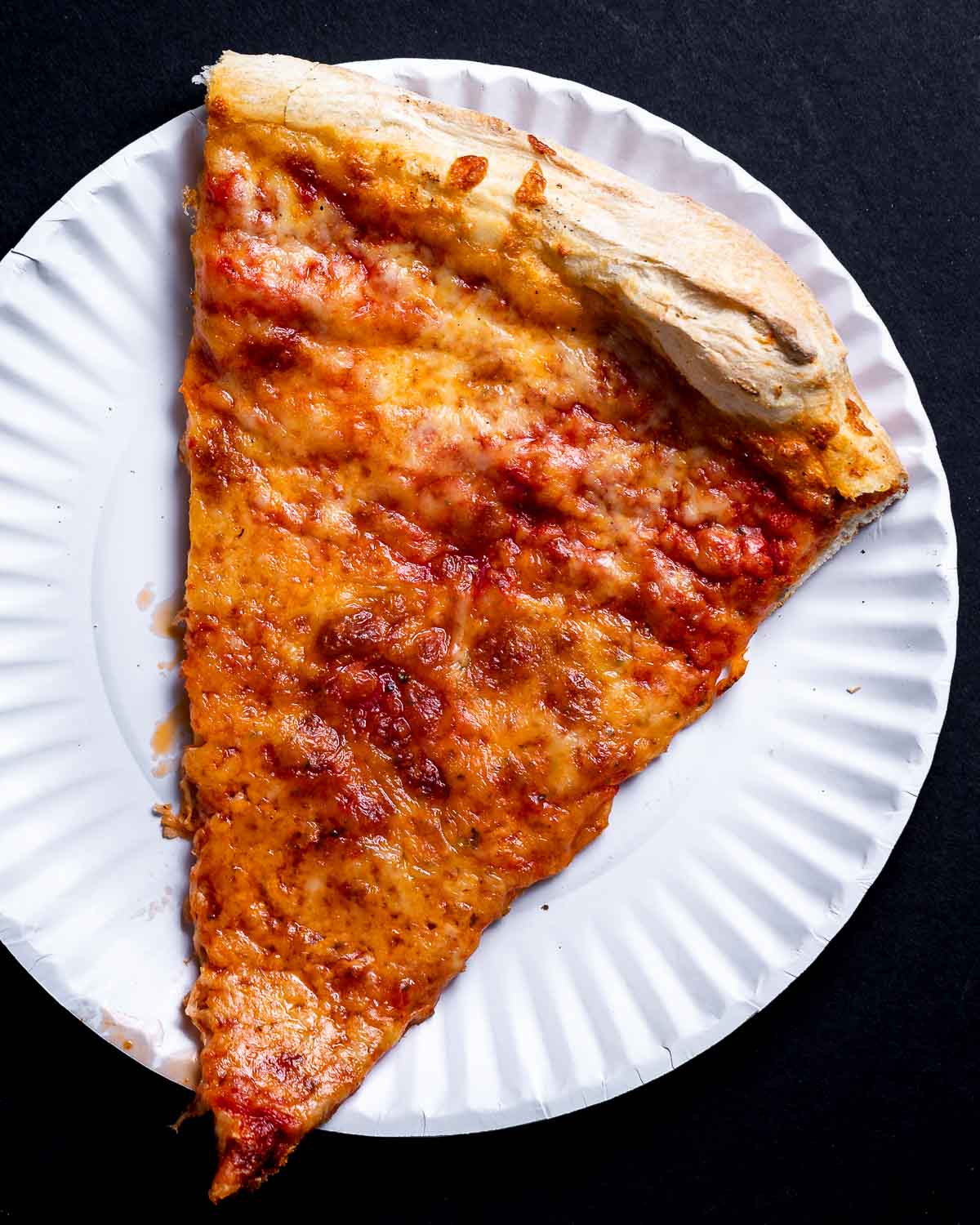 One slice of New York regular pizza in white plate.