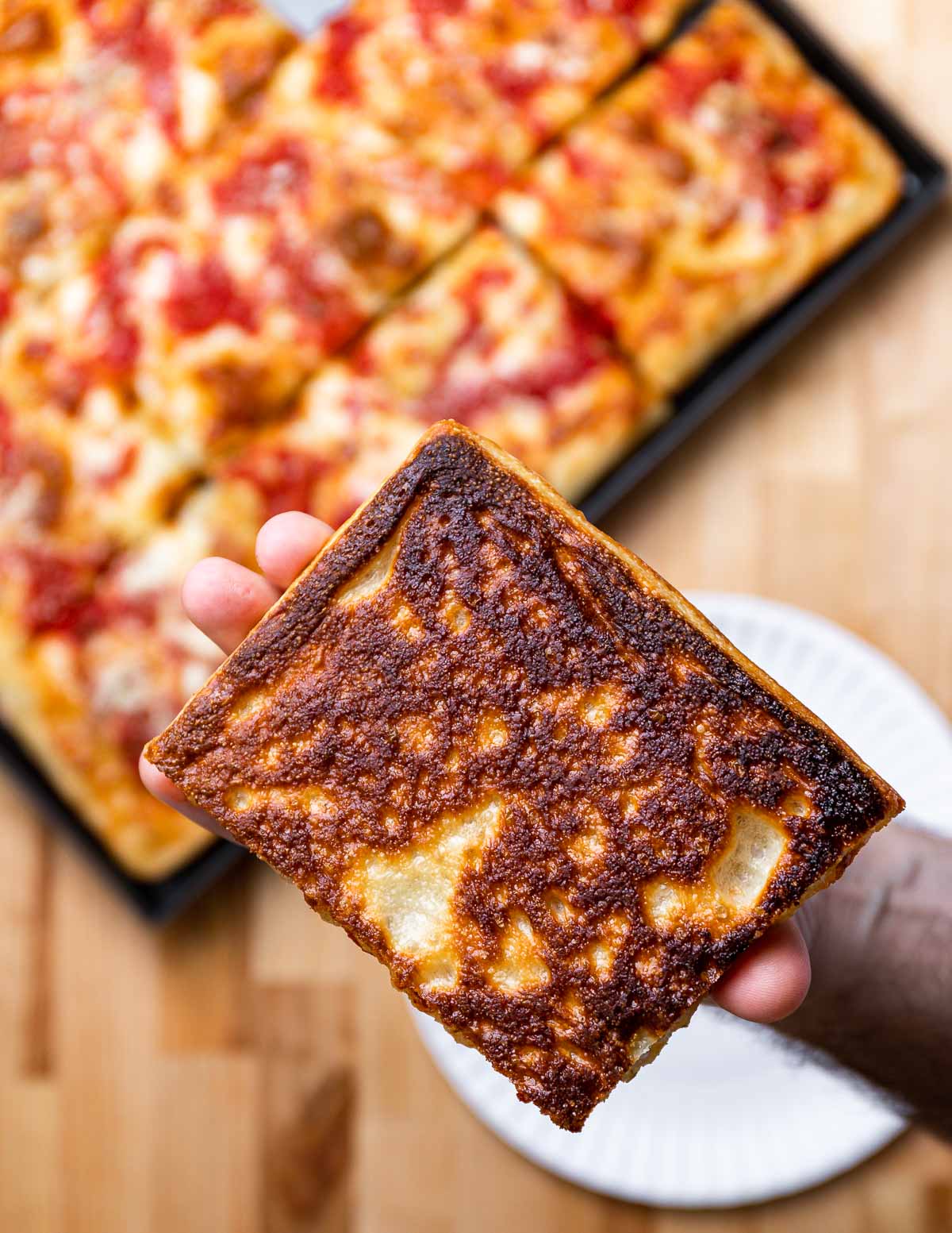 Crisp bottom of Grandma pizza held in hands.