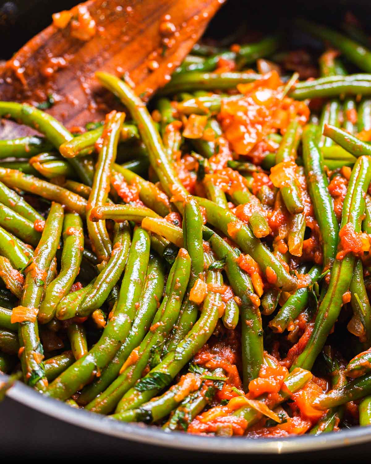 Pan full of green beans with tomato sauce.