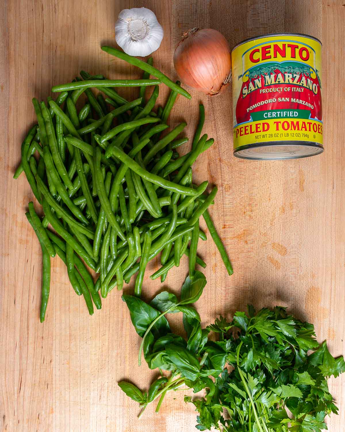 Ingredients shown: green beans, garlic, onion, can of plum tomatoes, basil, and parsley.