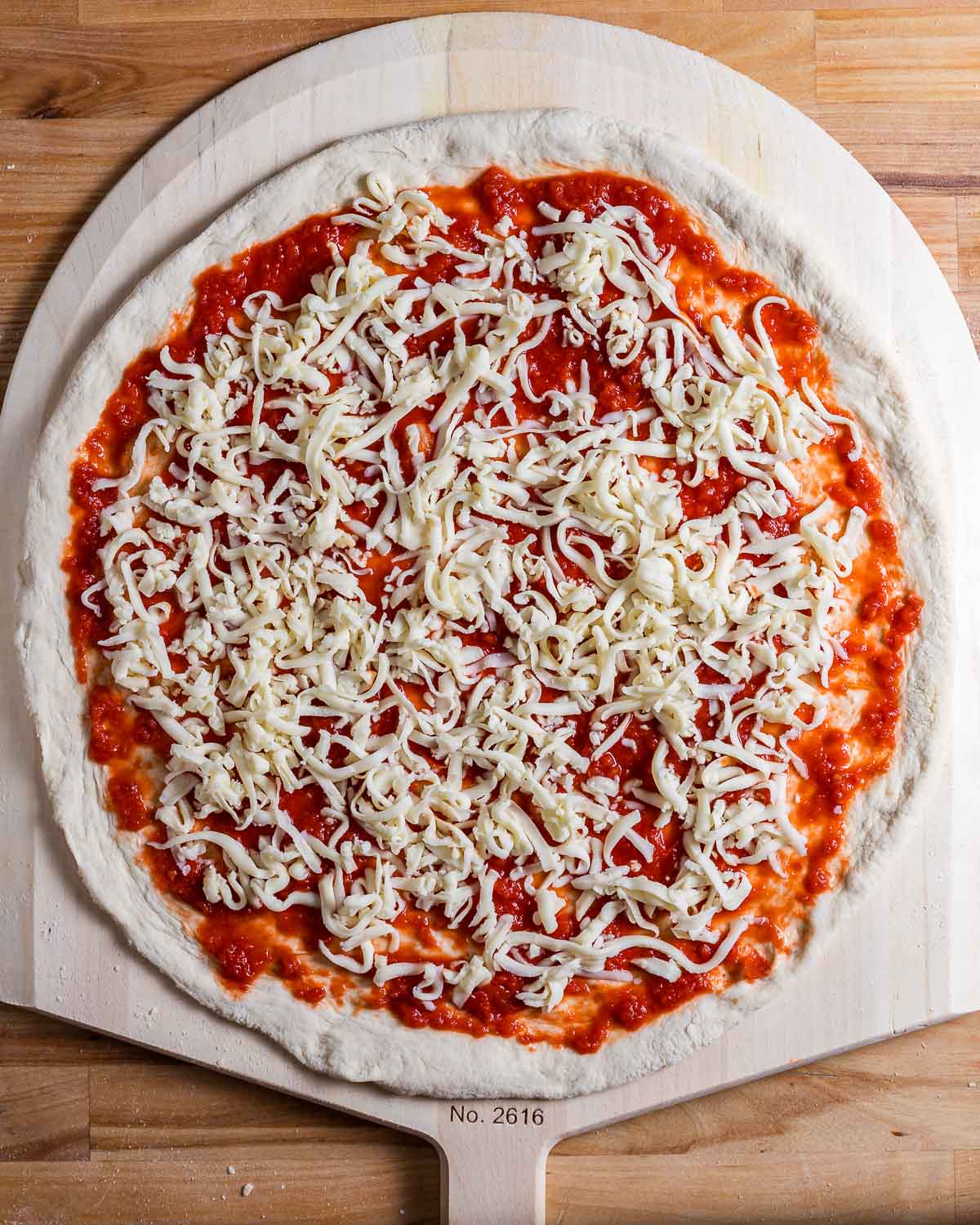 Uncooked pizza on wooden pizza peel.