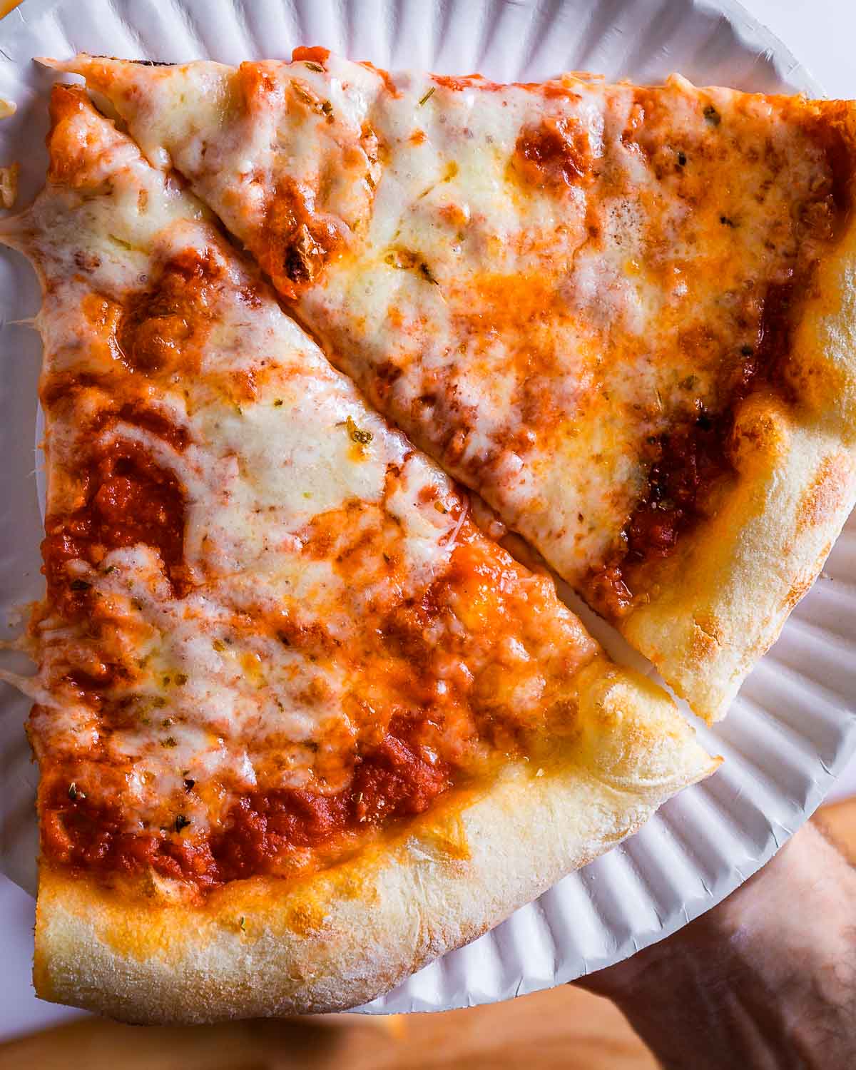 Two slices of homemade New York pizza held in plate.