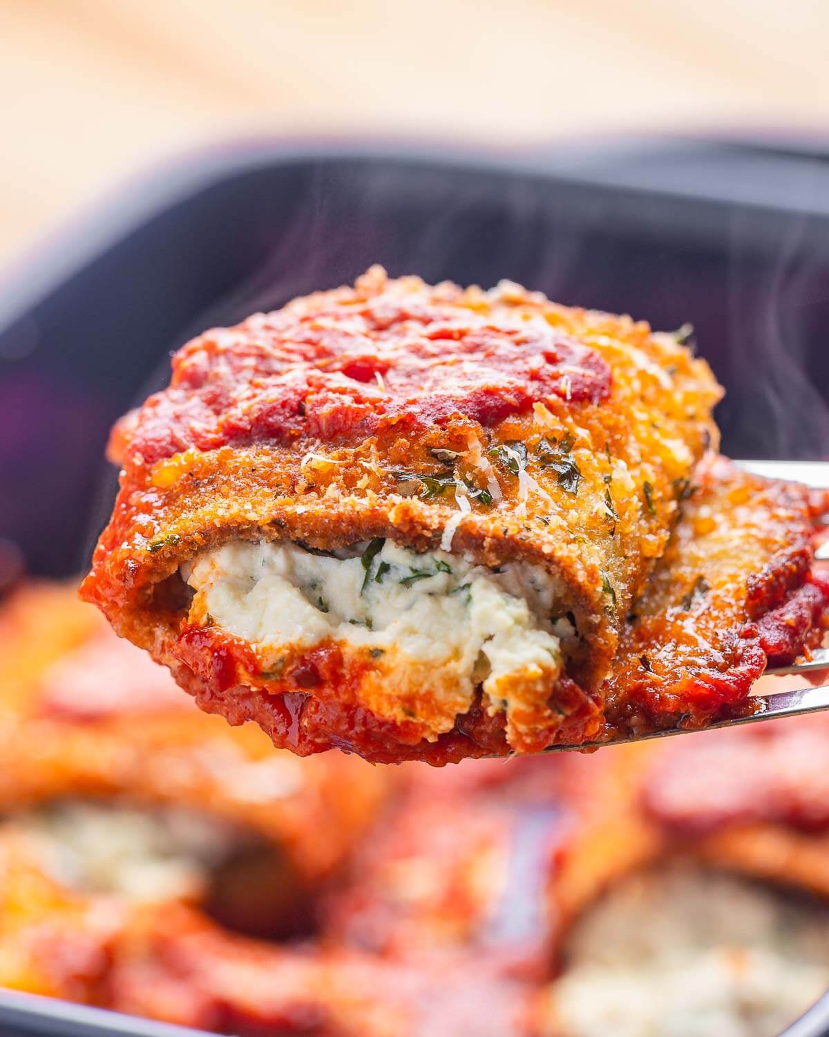 Spatula holding one piece of eggplant rollatini with steam showing.