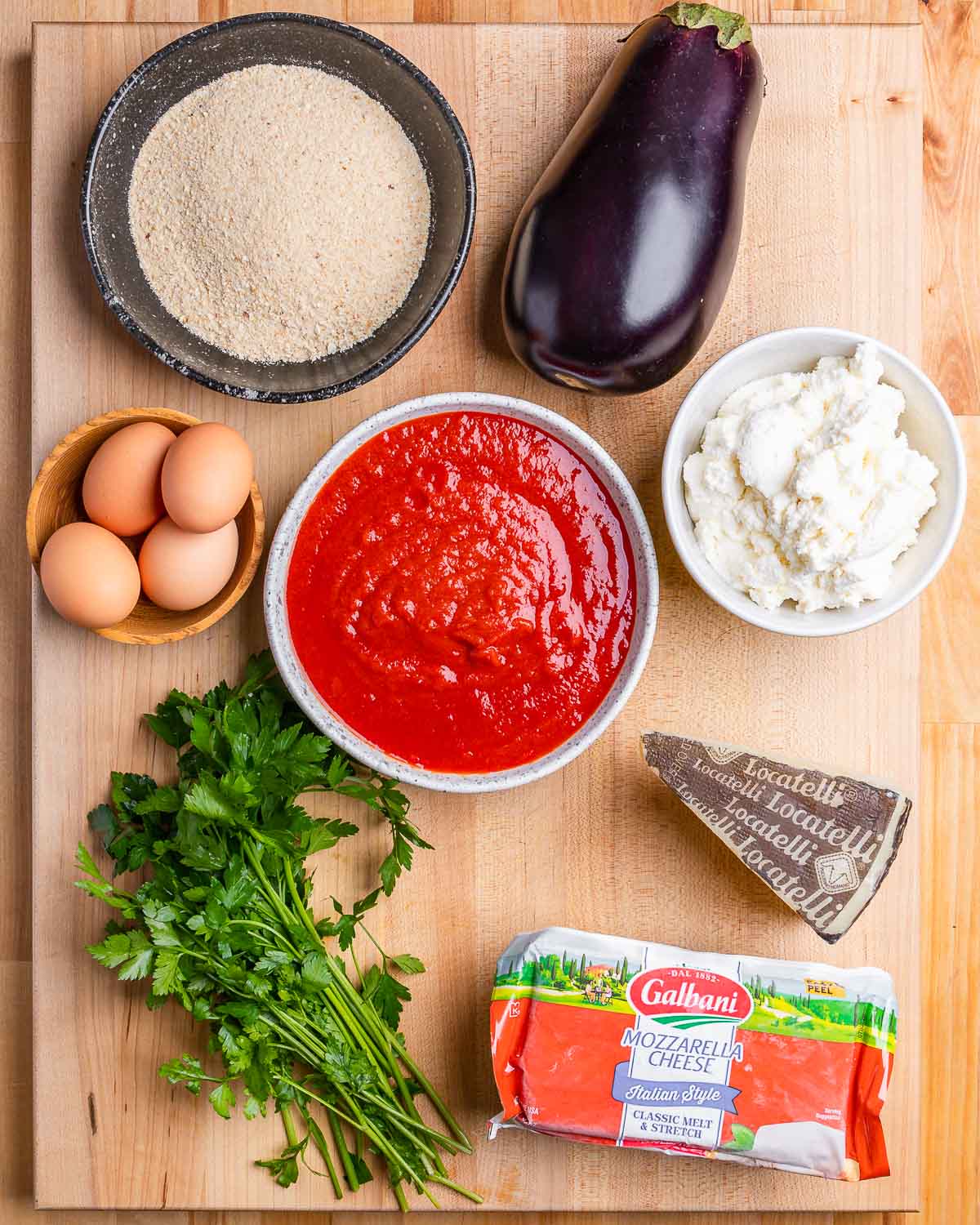 Ingredients shown: breadcrumbs, eggplant, eggs, marinara sauce, ricotta, parsley, Pecorino Romano, and mozzarella.