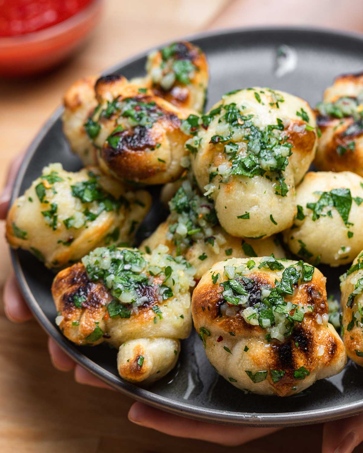 Garlic knots in grey plate held in hands.