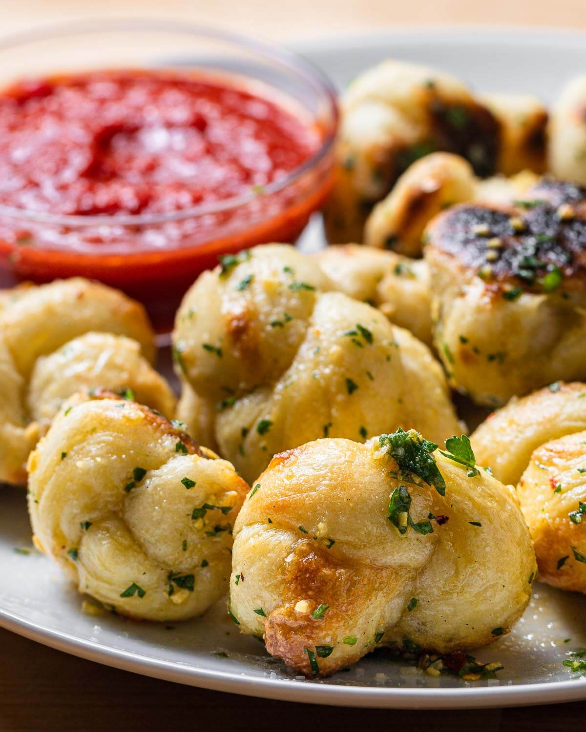 Garlic knots in white plate with dipping sauce.