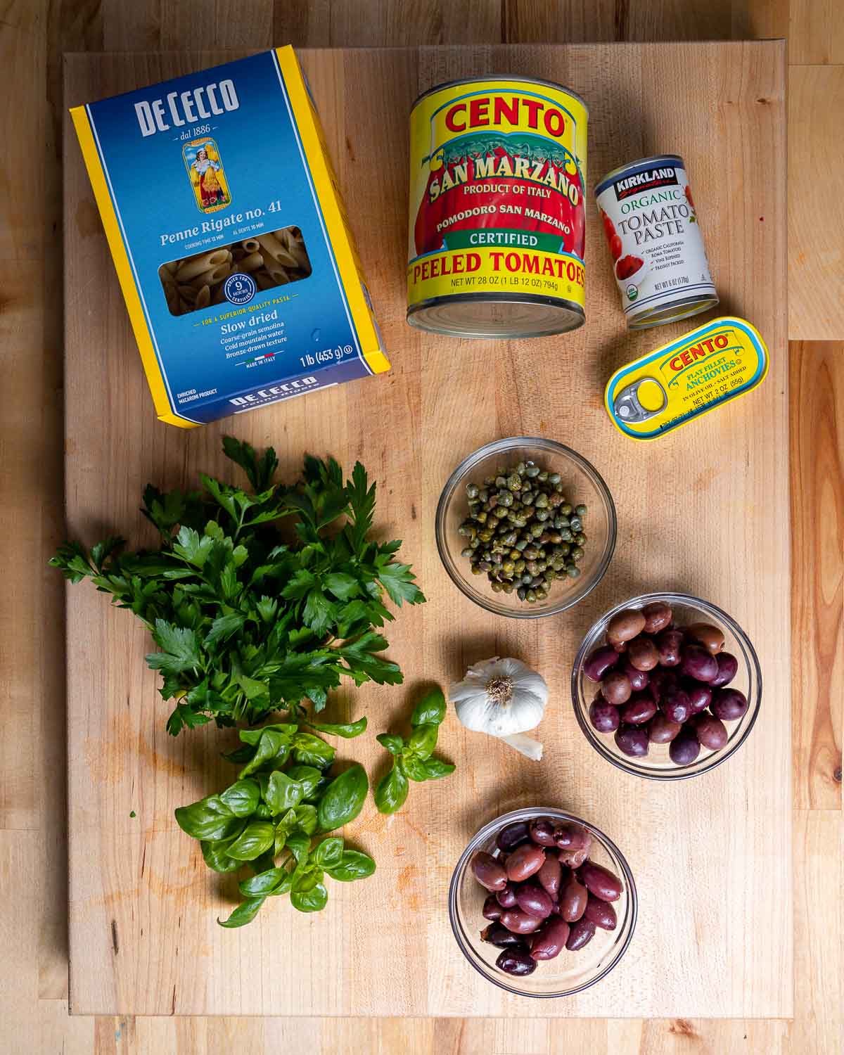 Ingredients shown: pasta, canned tomatoes, anchovies, capers, olives, garlic, herbs.