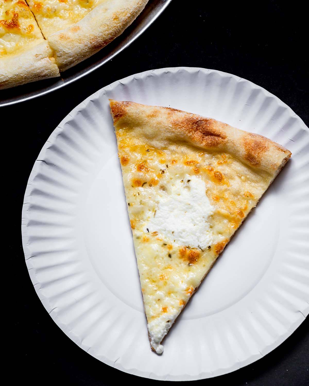 Slice of white pizza on white plate.
