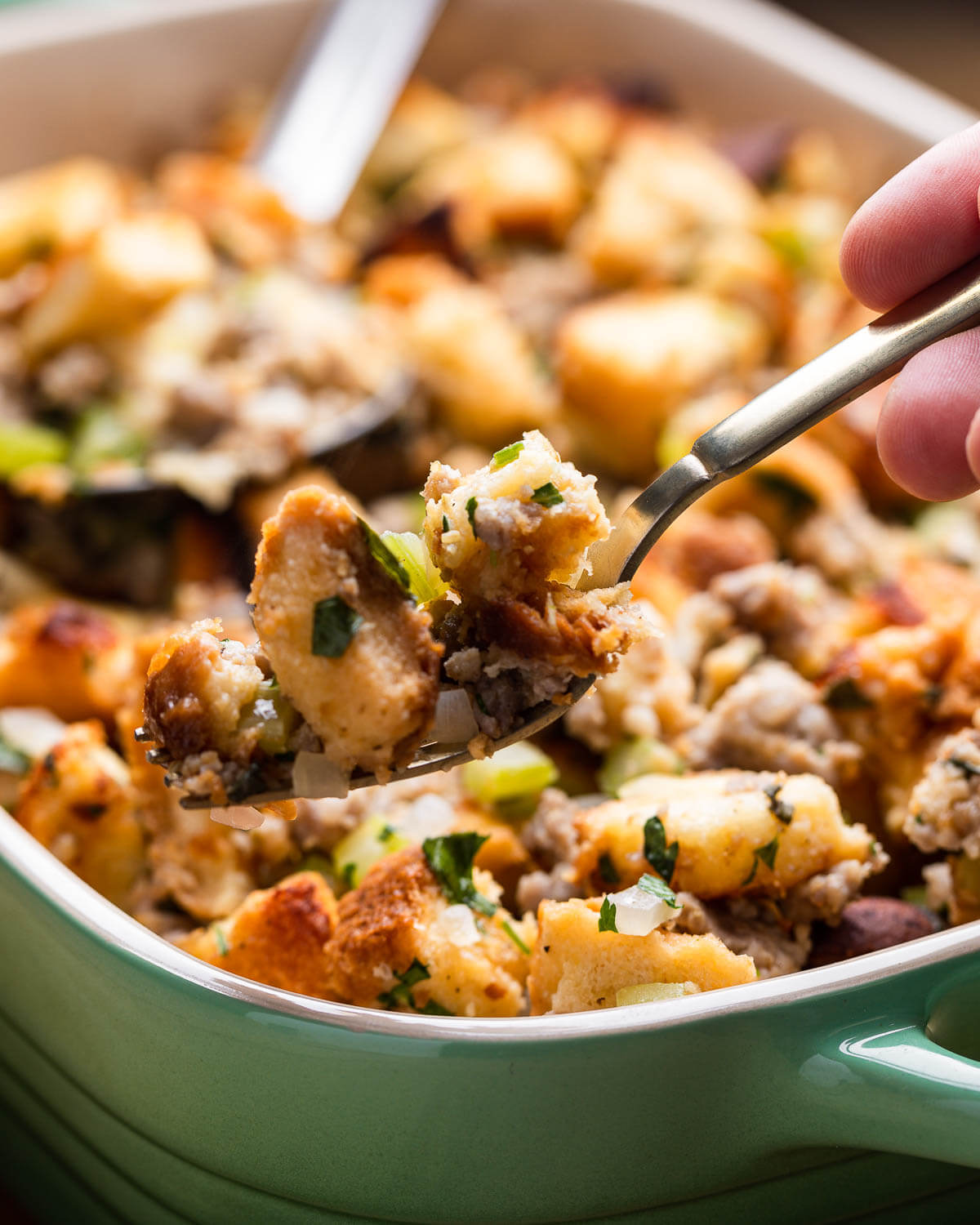 Hand holding fork with Italian sausage stuffing.