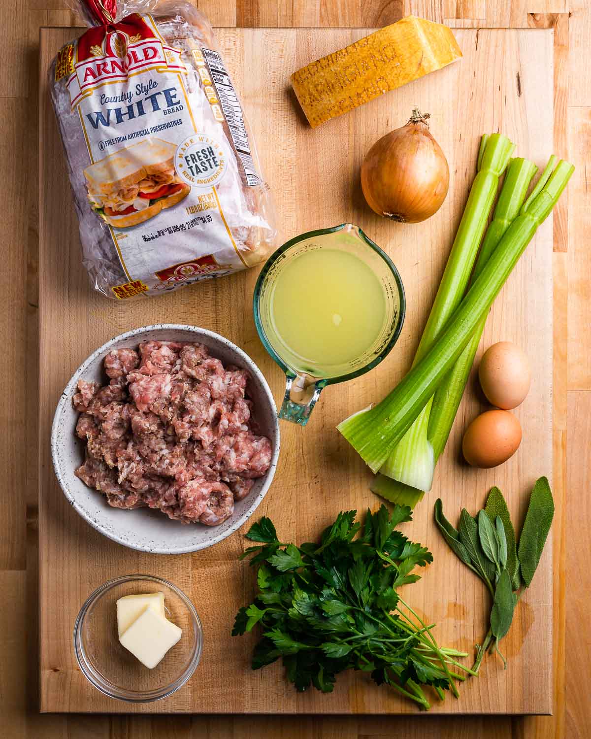 Ingredients shown: white bread, parmesan, onion, celery, chicken stock, sausage, butter, eggs, and herbs.