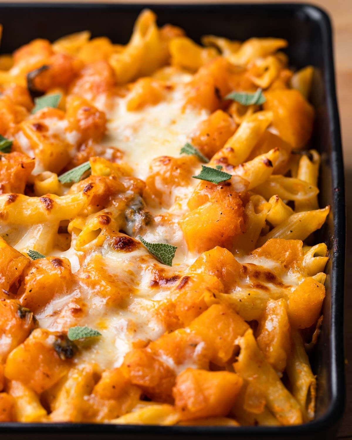 Black baking dish with baked butternut squash pasta.