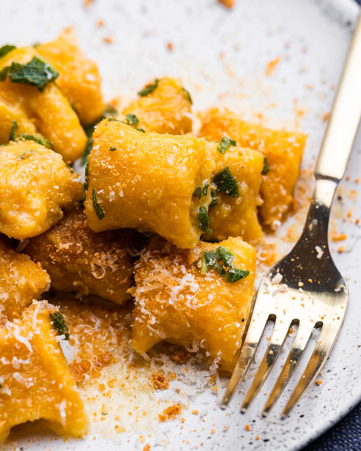 White plate with gold fork and butternut squash gnocchi.