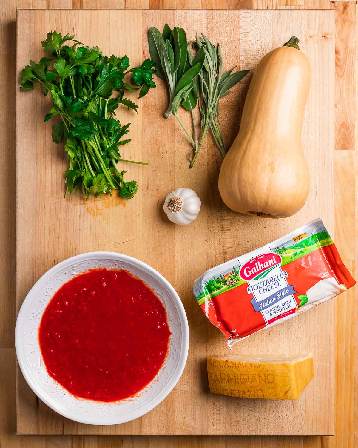 Ingredients shown: parsley, sage, butternut squash, garlic, sauce, mozzarella, and parmesan cheese.