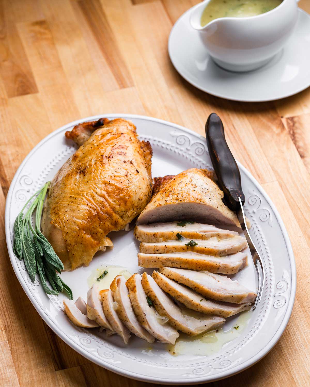 Platter with one carved and one uncarved turkey breast and carving fork.