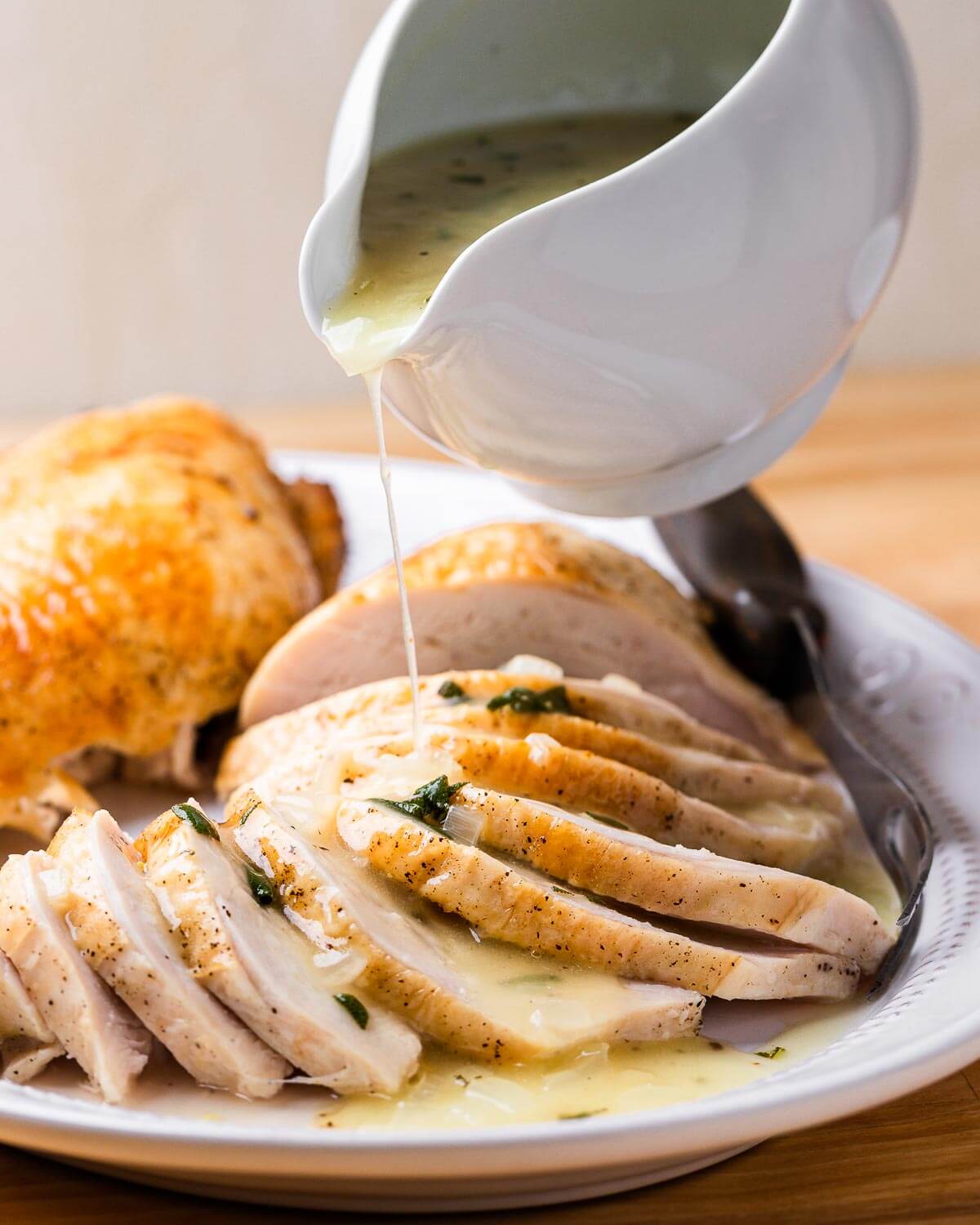 Gravy being poured on platter of carved turkey breast.