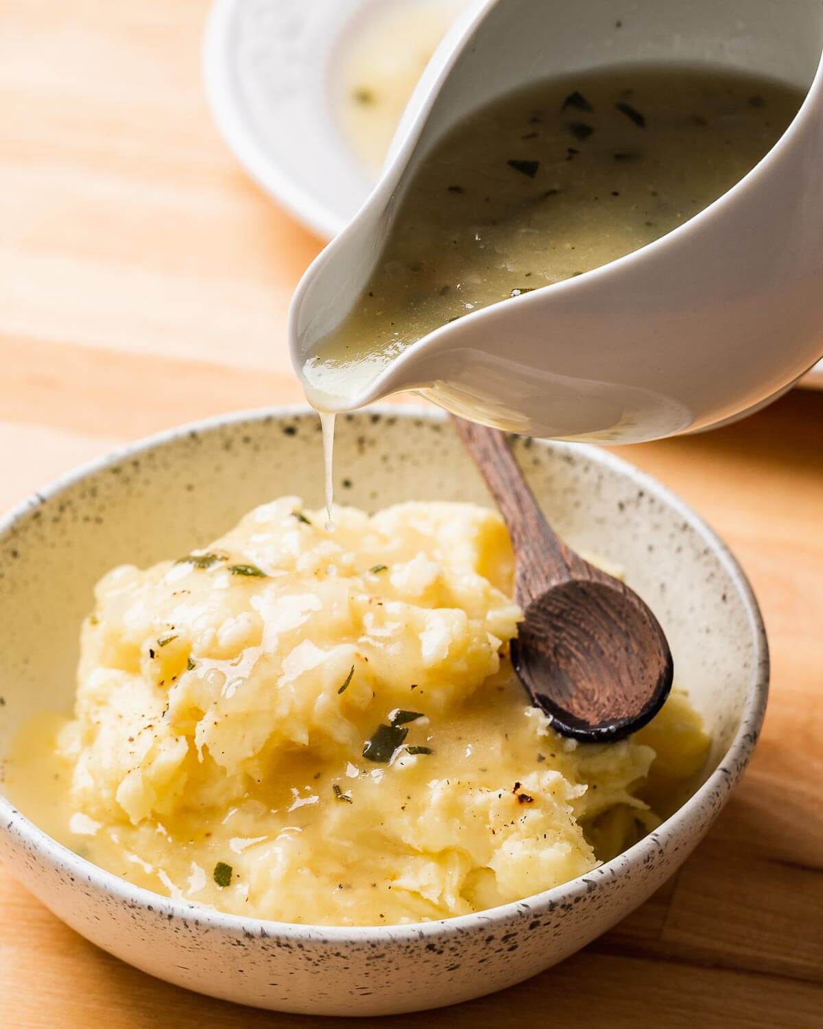 Gravy poured onto bowl of mashed potatoes.