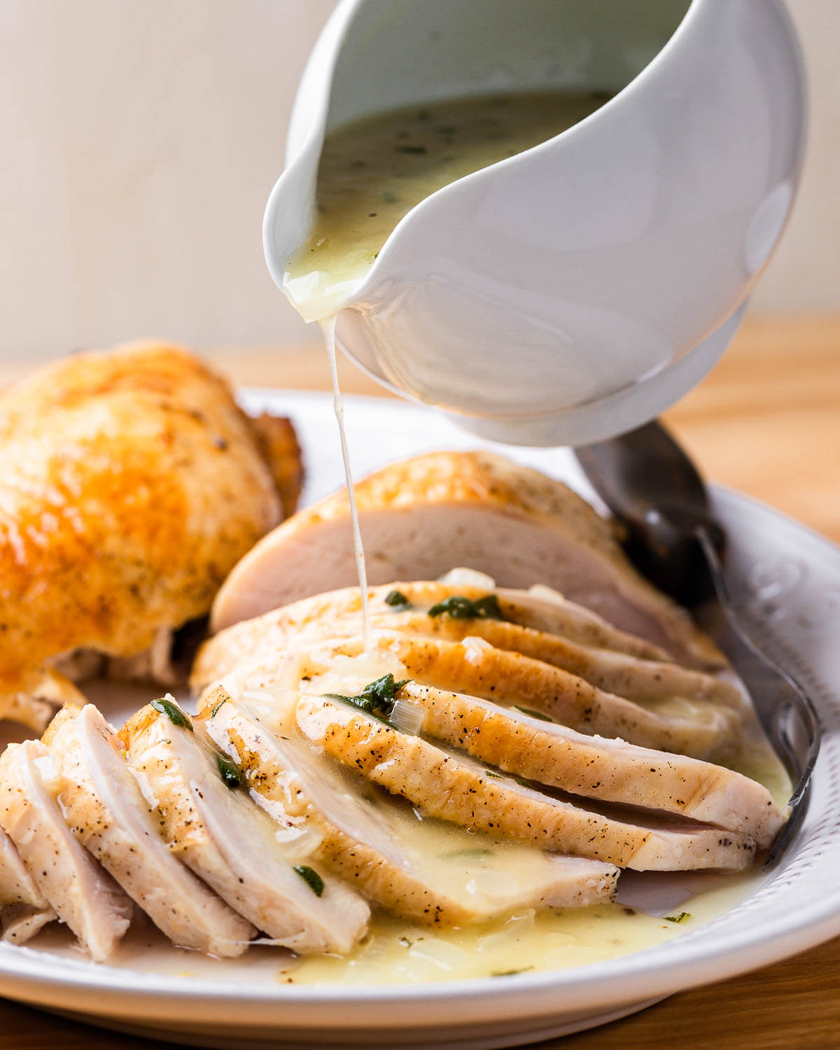 Turkey gravy being poured onto platter of turkey.