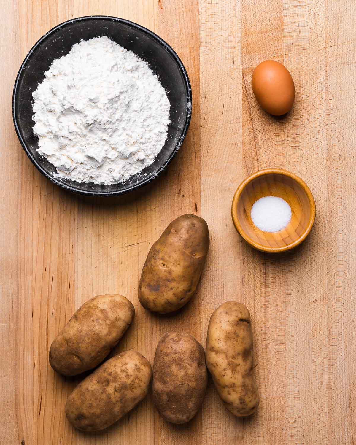 Ingredients shown: bowl of flour, egg, salt, and russet potatoes.