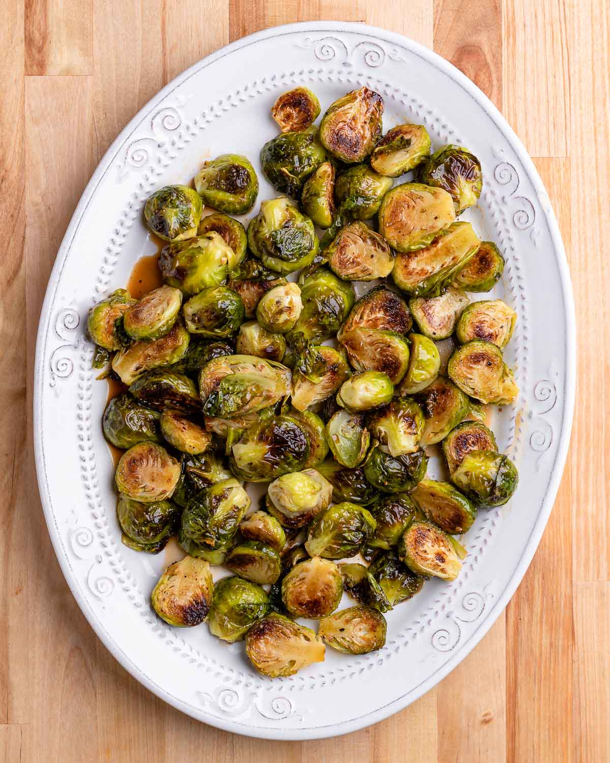 Roasted brussels sprouts in oval white plate on table.